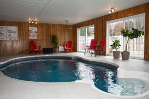 a large swimming pool in a room with red chairs at Travelodge by Wyndham Roberval in Roberval