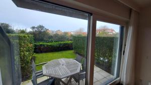 einen Tisch und Stühle auf einer Terrasse mit Glasschiebetür in der Unterkunft Residentie Koksijde promenade in Koksijde