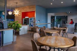 um restaurante com mesas e cadeiras e uma mulher ao fundo em Travelodge by Wyndham Roberval em Roberval