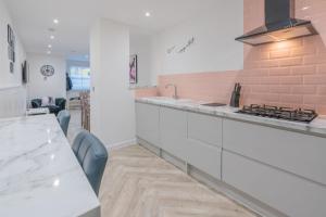 une cuisine avec des placards blancs et un comptoir dans l'établissement Four Bed House At Primal Estates Short Lets in Brighton, à Brighton et Hove