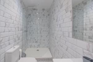 La salle de bains blanche est pourvue de toilettes et d'un miroir. dans l'établissement Four Bed House At Primal Estates Short Lets in Brighton, à Brighton et Hove