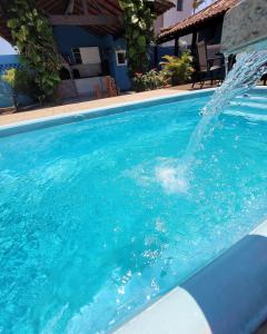 uma piscina com uma fonte de água em Hostel Maré Mansa em Cabo Frio