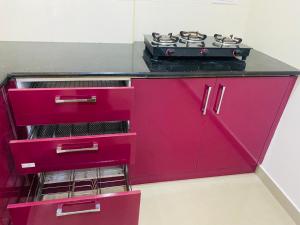 a pink kitchen with a stove on top of it at AL-Kabeer Heights in Kazhakuttam