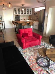 a living room with a red couch and a kitchen at Stylisches Maybach Appartement mit Terrasse für 5-7 Personen, 5 Betten, große Kochinsel, Homeoffice mit 250Mbit WLAN in Aidlingen