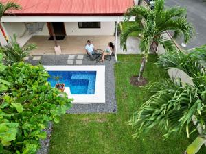 two people sitting in front of a house with a pool at Oasis Arenal Villa Pool & Arenal Volcano View in Fortuna