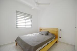 Cama en habitación blanca con ventana en Appartement neuf en loma, en Las Terrenas
