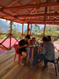 a group of people sitting at a table eating food at the wooden house choquequirao in Cachora