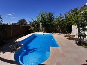 a blue swimming pool in a backyard with a fence at PATO BLANCO in Ciudad Lujan de Cuyo