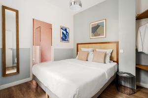 una camera con letto bianco e specchio di Edgar Suites Grands Boulevards - Hauteville a Parigi