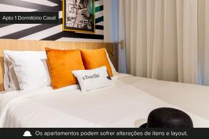 a bed with orange and white pillows on it at Charlie Uwin Brooklin in Sao Paulo
