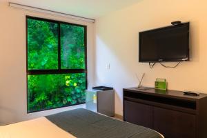 a bedroom with a large window and a flat screen tv at Termales Santa Rosa De Cabal in Santa Rosa de Cabal