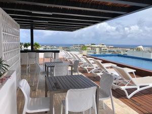 a patio with white chairs and tables and a swimming pool at Modern Studio close to the beah Pool and Fast WiFi in Playa del Carmen