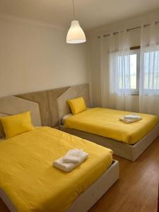 - 2 lits dans une chambre avec des draps jaunes dans l'établissement Extraordinary Holiday House at Fernão Ferro!, à Fernão Ferro