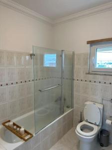 La salle de bains est pourvue de toilettes et d'une douche en verre. dans l'établissement Extraordinary Holiday House at Fernão Ferro!, à Fernão Ferro