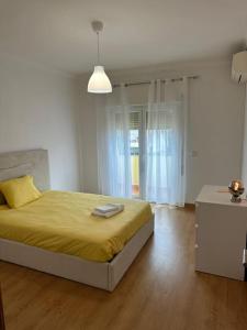 - une chambre avec un grand lit et une couverture jaune dans l'établissement Extraordinary Holiday House at Fernão Ferro!, à Fernão Ferro