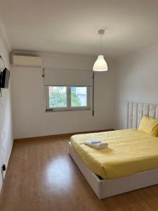 - une chambre avec un grand lit et une couverture jaune dans l'établissement Extraordinary Holiday House at Fernão Ferro!, à Fernão Ferro