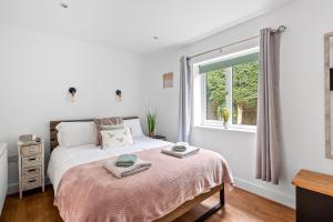 a white bedroom with a bed with a window at Lytton Tree Lodge Reydon in Reydon