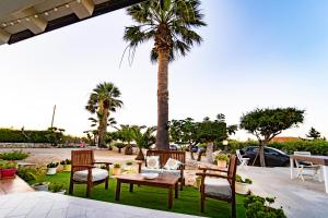 een patio met een tafel en stoelen en een palmboom bij Kòre rooms in Castellammare del Golfo