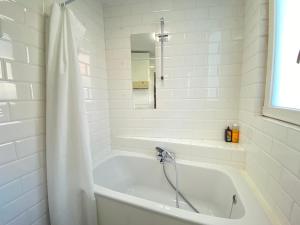 a white bath tub with a shower curtain in a bathroom at Charming National Street Room in the Heart of Antwerp in Antwerp
