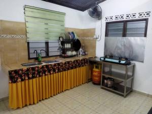 cocina con encimera, fregadero y ventana en Ustazah Homestay, en Kampong Ru Sepuloh