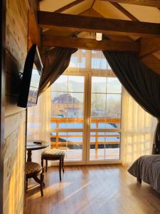 a bedroom with a large window and a bed and a table at Cottage Familiya in Verkhovyna