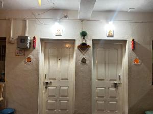 a room with two white doors and a tv at Shriguru Guest House Akkalkot in Akalkot
