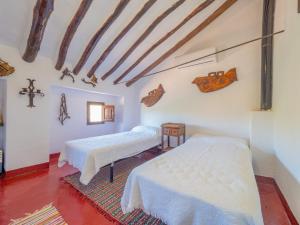 two beds in a room with a cross on the wall at Cubo's Cortijo El Perezon in Archidona