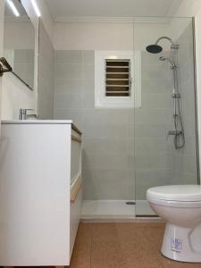 uma casa de banho branca com um chuveiro e um WC. em Como en Casa 2 em Santa Pola