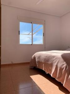 biały pokój z łóżkiem i oknem w obiekcie Como en Casa 2 w mieście Santa Pola