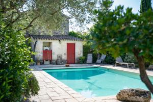 een zwembad voor een huis met een rode deur bij aMiniMas Eco gîtes in Le Garn