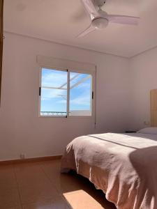 a white bedroom with a bed and a window at Como en Casa 2 in Santa Pola