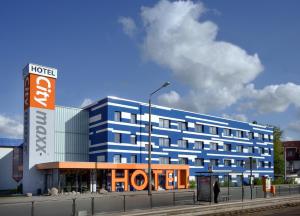 a blue hotel with a man standing in front of it at Hotel Citymaxx in Rostock