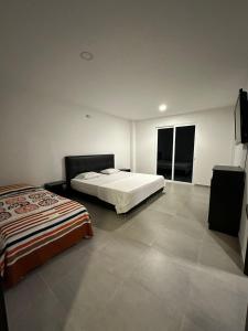 1 dormitorio con 2 camas y TV de pantalla plana en FINCA EL GALEM, en Guamal