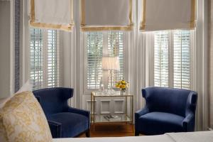 two blue chairs and a table in a bedroom with windows at Hamilton Turner Inn in Savannah