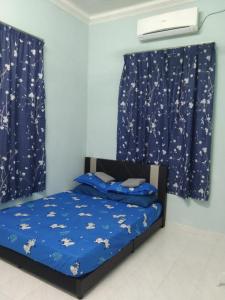 a bedroom with a bed with blue sheets and curtains at Ammar Homestay Tok Bali in Kampong Ayer Tawar