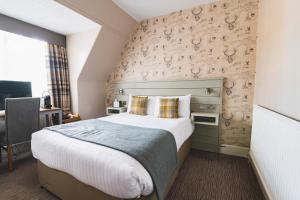 a bedroom with a large bed in front of a wall at Tullie Inn in Balloch