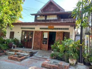 a house with wooden doors and plants in front of it at watthat & Maladress GUESTHOUSE in Luang Prabang