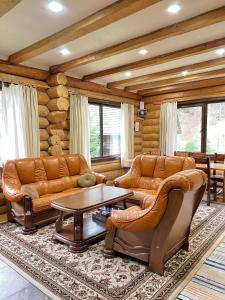 a living room with leather furniture and a table at Guest House in Synevyrsʼka Polyana