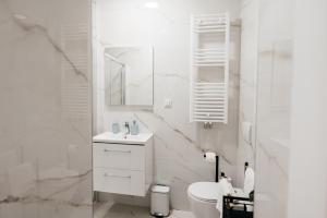 a white bathroom with a sink and a toilet at KM Apartments in Zagreb
