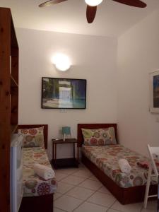 a bedroom with two beds and a tv on the wall at Hostels Holiday Cape Verde in Santa Maria