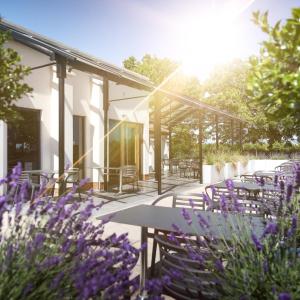 un patio con mesas, sillas y flores púrpuras en Foxfields Country Hotel, en Langho