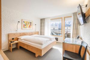 um quarto com uma cama grande e uma janela em Hauser Hotel St. Moritz em St. Moritz