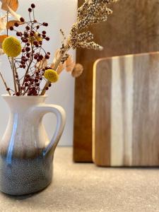 a white vase with flowers in it on a counter at Cosy Concept - nahe Hamburg in Pinneberg