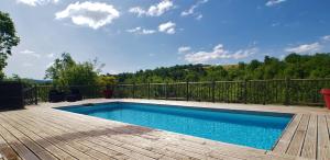 una piscina en una terraza de madera junto a una valla en Gîte de Cayssie, en Verrières