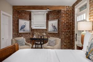 a bedroom with a bed and chairs and a brick wall at Hamilton Turner Inn in Savannah
