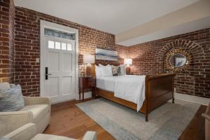 a brick walled bedroom with a bed and a couch at Hamilton Turner Inn in Savannah
