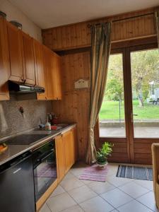 una cocina con armarios de madera y una gran ventana en Appartamento a Monclassico, en Monclassico