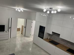 a large kitchen with white cabinets and a television at Apartament Magnoliowy in Owińska