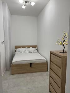 a bedroom with a bed and a dresser with a plant at Apartament Magnoliowy in Owińska