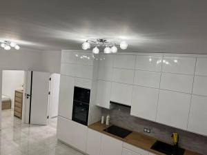 a kitchen with white cabinets and a ceiling at Apartament Magnoliowy in Owińska